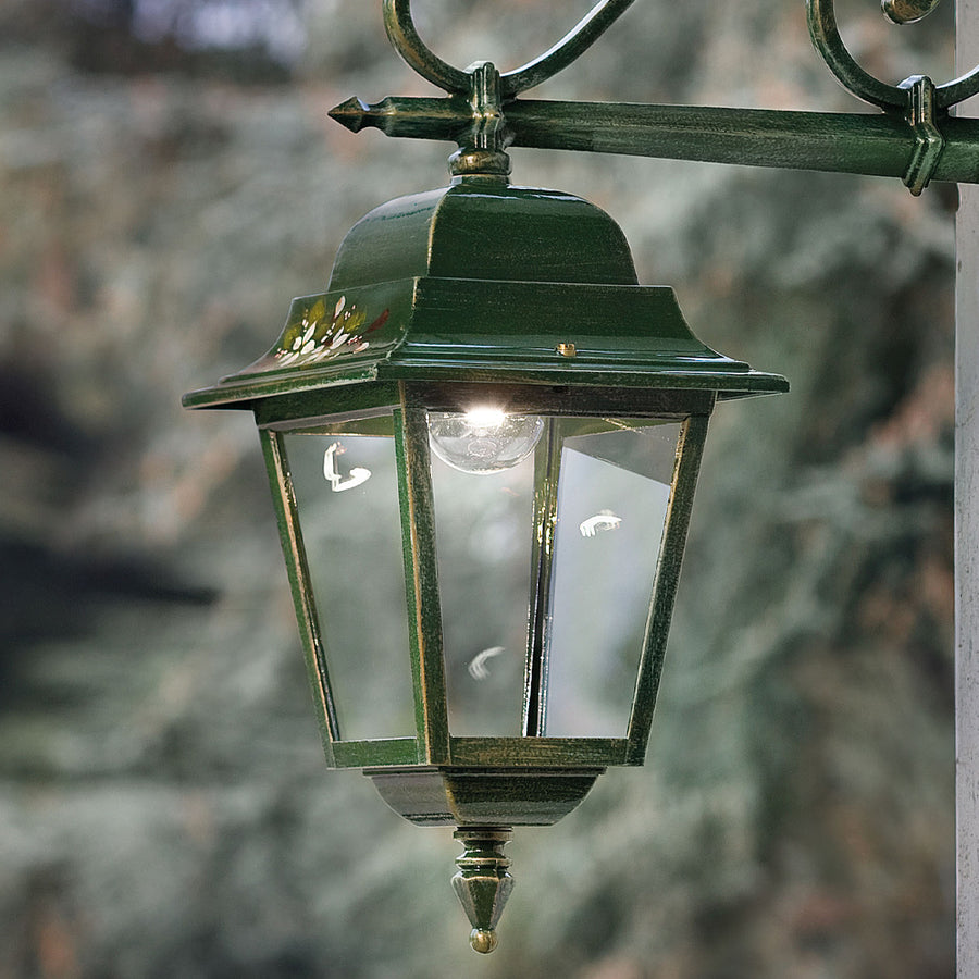 Ferroluce Gorizia kültéri fali lámpa üzem közben, oldalnézetből fotózva, a klasszikus lámpatest üvegablakai visszaverik a fényt.