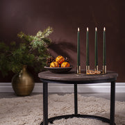 Zöld LED gyertya szett ünnepi enteriőrben, arany gyertyatartóval, fenyőágakkal és illatos narancsdíszekkel dekorált asztalon