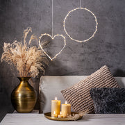 Bézs Flow LED gyertyák tálcán elhelyezve egy modern nappaliban, dekorációs világítással és száraz növényes vázával – meleg, meghitt otthoni hangulat