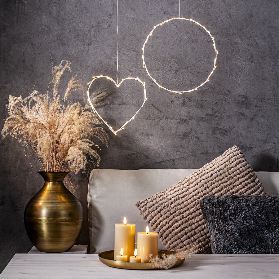 Bézs Flow LED gyertyák tálcán elhelyezve egy modern nappaliban, dekorációs világítással és száraz növényes vázával – meleg, meghitt otthoni hangulat