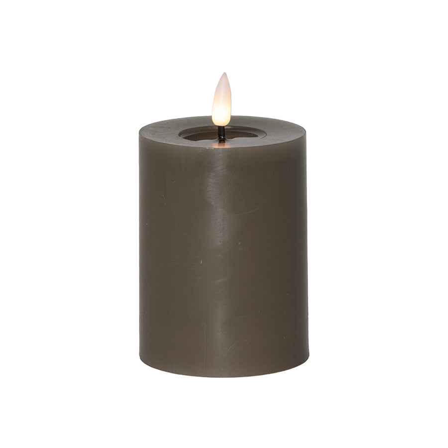 Szürkésbarna, henger alakú LED gyertya meleg fehér lánggal, fehér háttér előtt, 12,5 cm magas kivitelben.