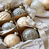 Kézzel készített pezsgőszínű üvegdíszek közelről, díszdobozban, masnis szalaggal átkötve.