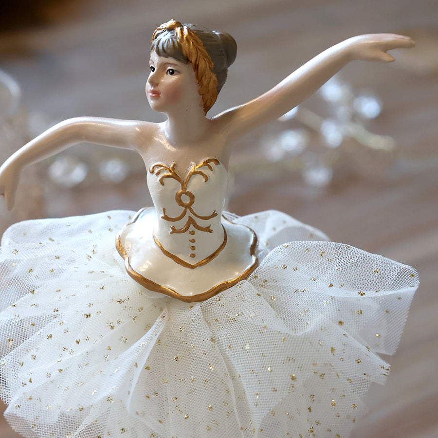 A First Snow balerina kézzel festett arcának, aranymintás ruhájának és csillogó pöttyös tüllszoknyájának közeli részlete.