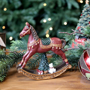 Bordó karácsonyi hintaló figura a Christmas Heritage kollekcióból, karácsonyi díszekkel körülvéve