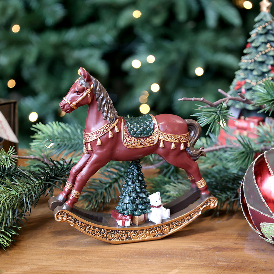 Bordó karácsonyi hintaló figura a Christmas Heritage kollekcióból, karácsonyi díszekkel körülvéve