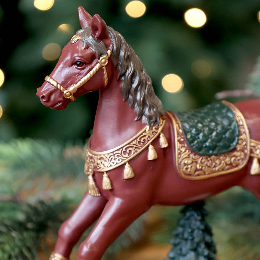 Közelkép a bordó hintaló arany díszítésű nyergéről és kantárjáról