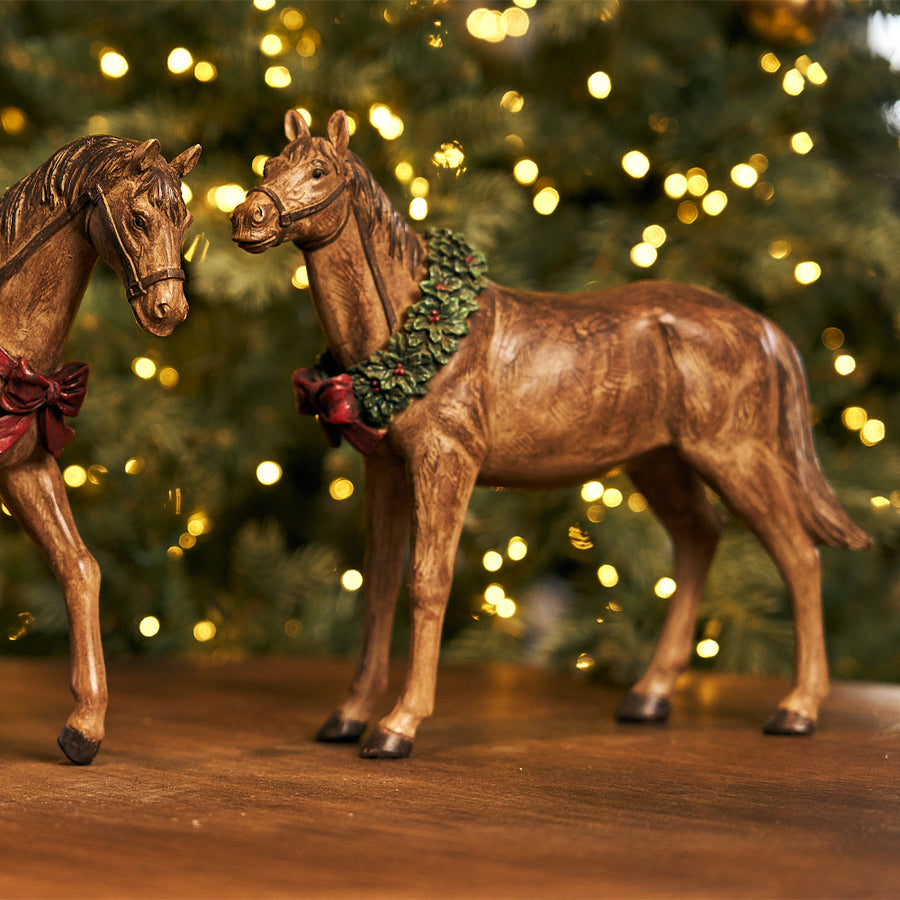 Ünnepi koszorúval díszített, barna színű, karácsonyi dekor lovacska.