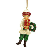 HERITAGE karácsonyi téli kisfiú figura karácsonyfadísz ajándékkal és koszorúval, 10 cm