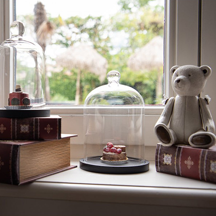 Antikolt maci figura vintage dekorációval, könyvek és üveg búra mellett.