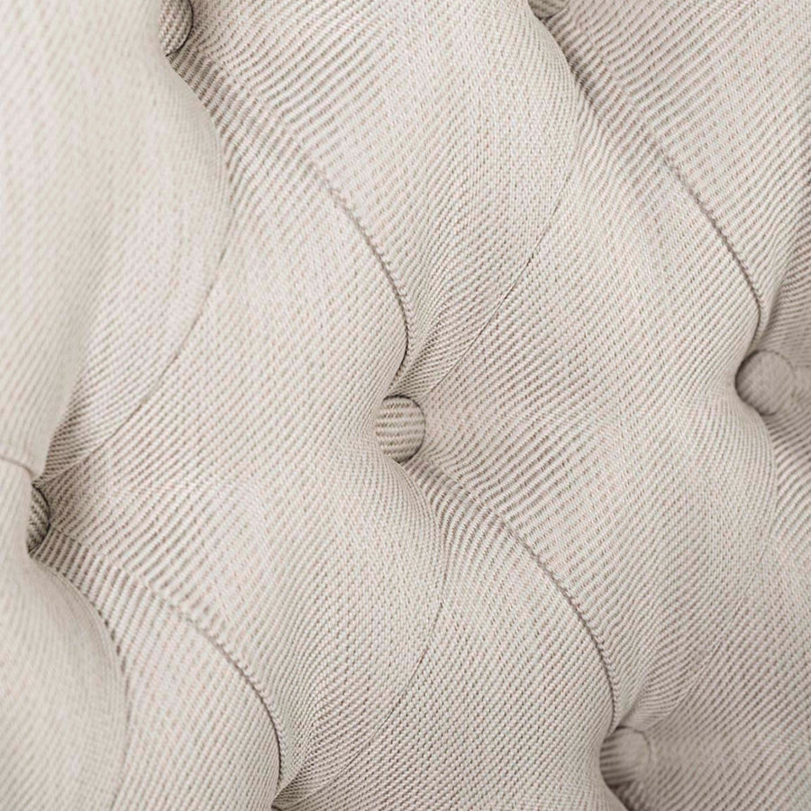 Közelkép a gombos tűzésű bézs kárpitozásról a HERITAGE fotel háttámláján.