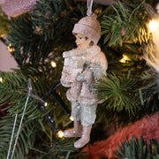 Heritage pink téli kisfiú karácsonyfadísz közeli fotója a karácsonyfa ágán, csillogó fények között.