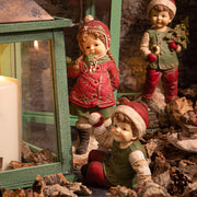 HERITAGE karácsonyi téli kisfiú figura díszletben, zöld lámpás és ünnepi kiegészítők között.