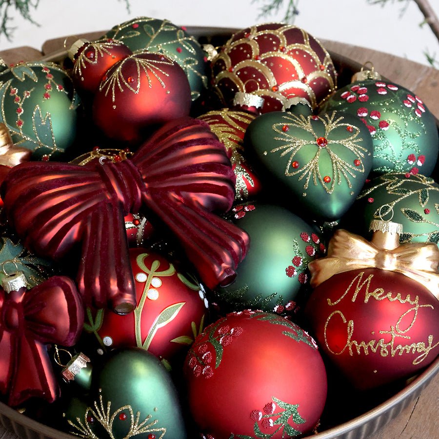 Zöld gyöngyös levélmintájú Heritage üveggömb más növényi mintás díszek és zöld szívdísz társaságában.