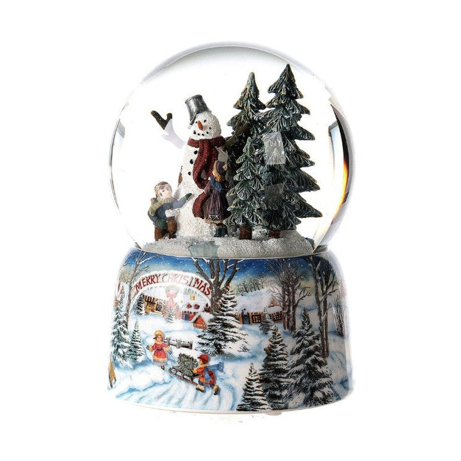 Karácsonyi zenélő-forgó hógömb, téli havas erdőben hóembert építő gyerekekkel.