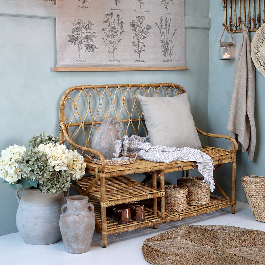 Vintage stílusú előtér, rattan pad és nagyméretű váza krémszínű hortenziákkal.