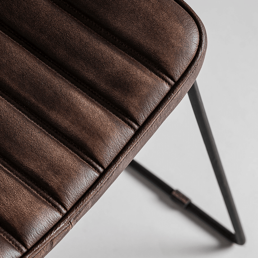 Közelkép a sötétbarna bőr ülőfelületről és az acélszerkezetről.