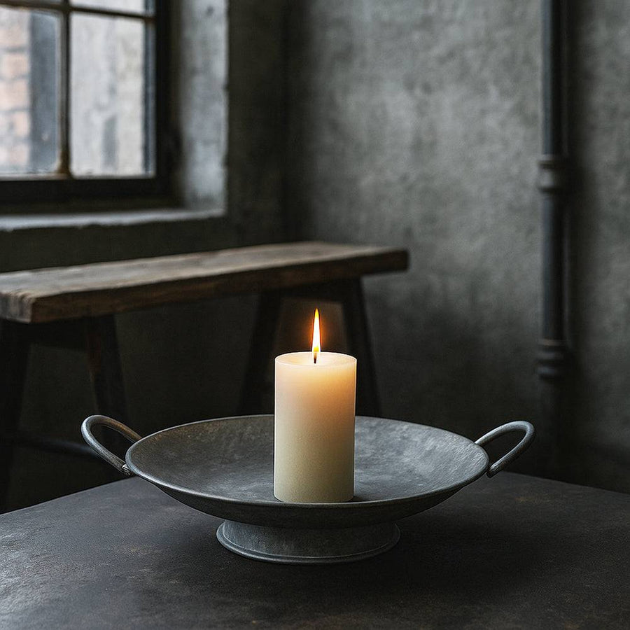 JUNKER szürke bádog tál égő gyertyával, ipari stílusú enteriőrben, nyers falakkal és fa paddal a háttérben.