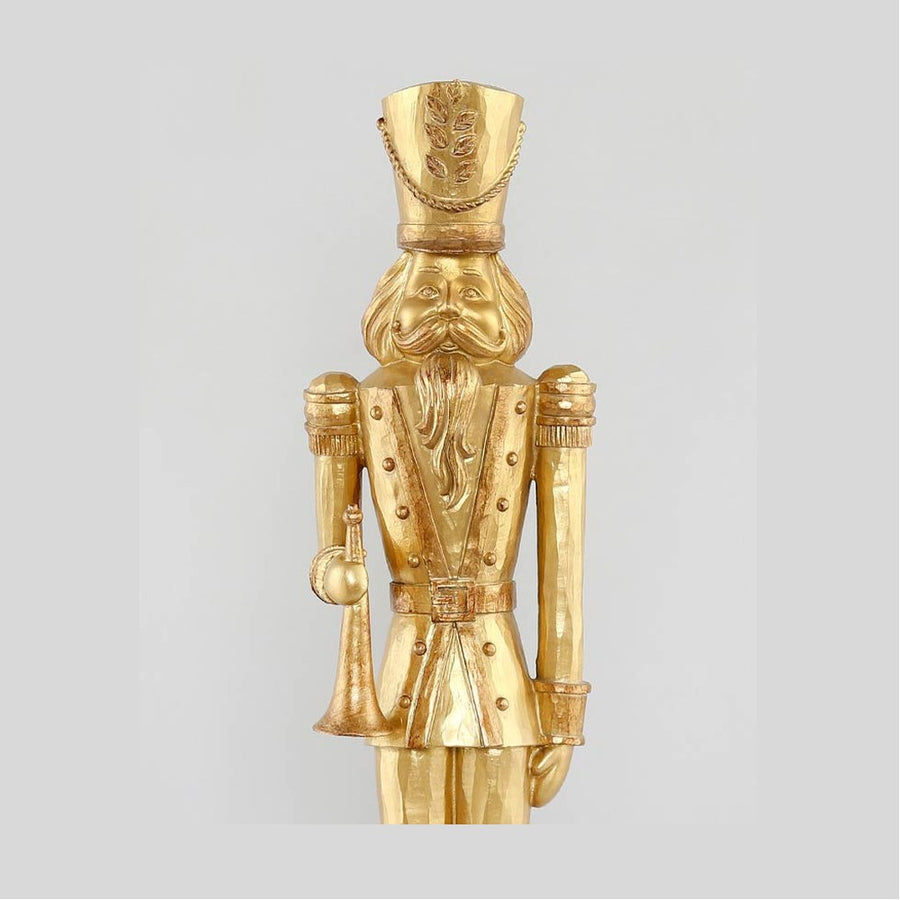 Arany színárnyalatú, faragott fahatású karácsonyi diótörő figura.