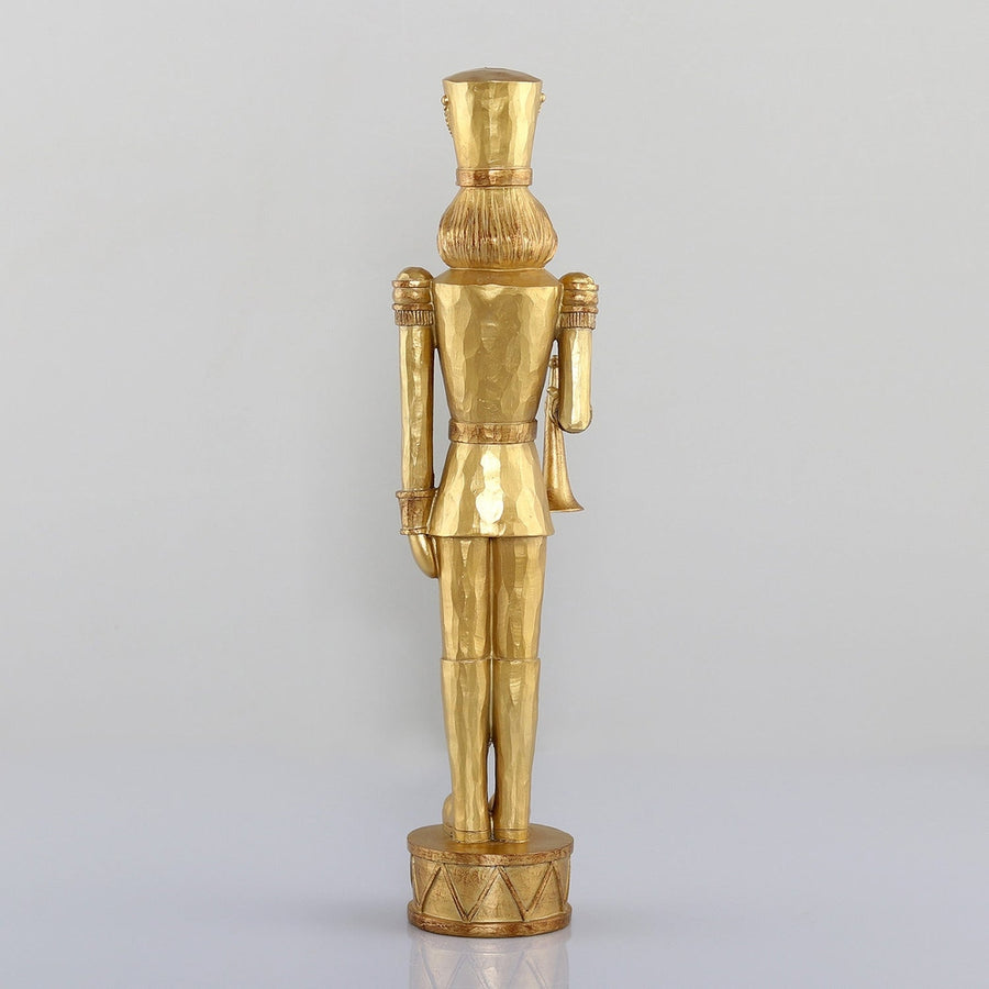 Arany színárnyalatú, faragott fahatású karácsonyi diótörő figura.