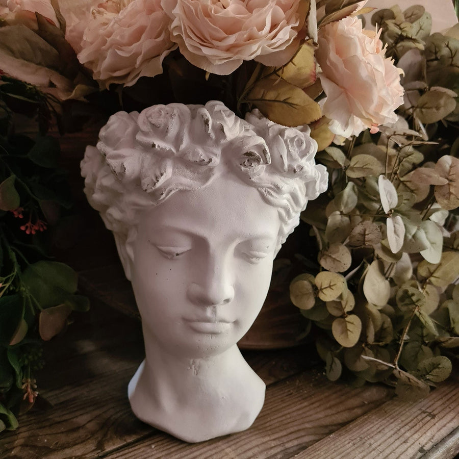 Antikolt felületű, krém színű kaspó büszt.