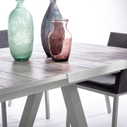 Krém színű kortárs kerti étkezőasztal. színes üveg vázákkal.