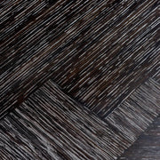 Faszénfekete színű tölgyfurnérból és bronz felületű rozsdamentes acélból készült, ovális formájú design étkezőasztal.