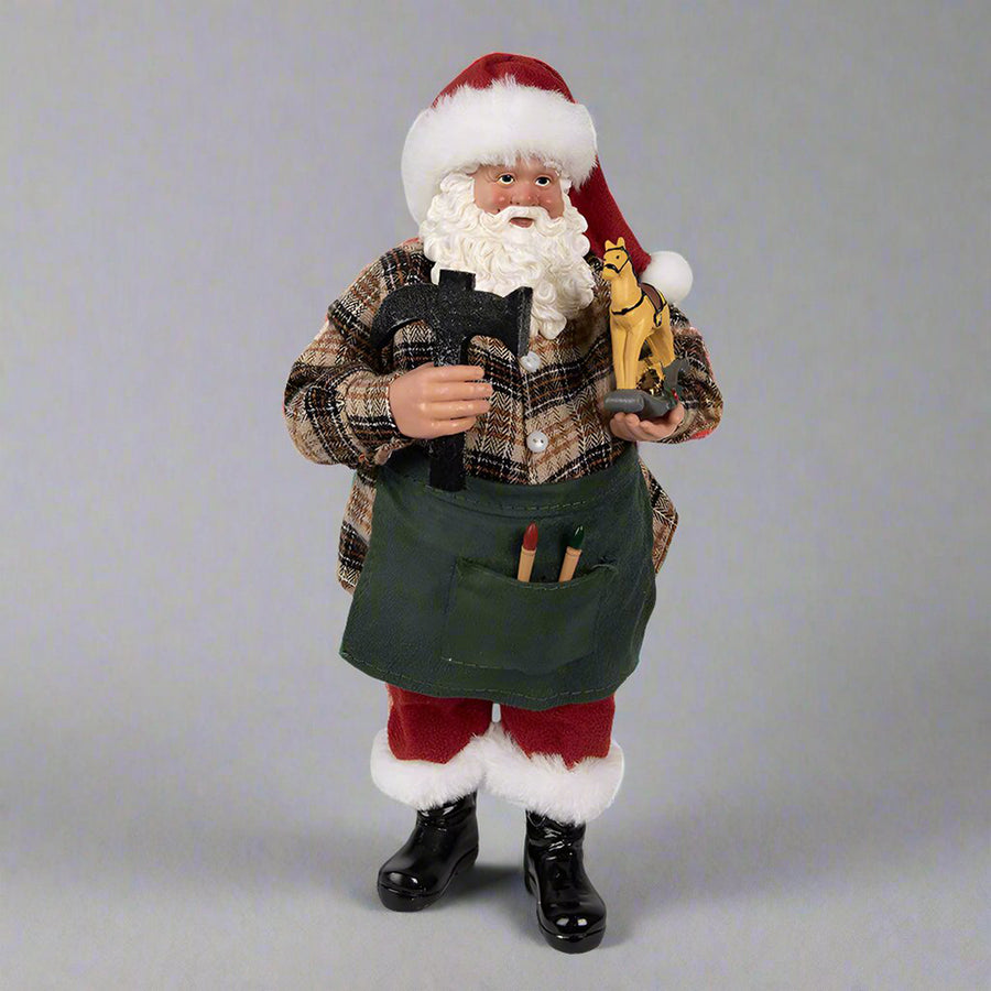 Játékkésszító Mikulás figura, kockás ingben, zöld kötényben, kezében kalapáccsal és hintalóval.