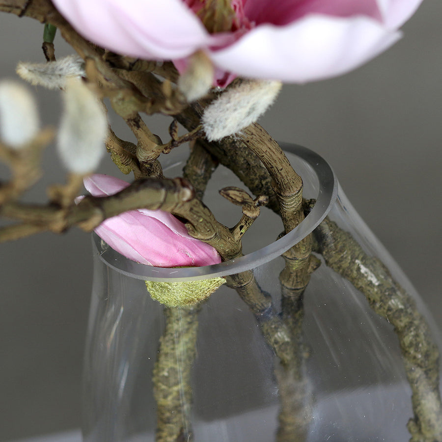 Halvány rózsaszín színű, mű magnólia kompozíció, modern formájú üvegvázában..