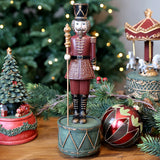 NOÉL zenélő karácsonyi diótörő figura ünnepi környezetben, karácsonyfa mellett