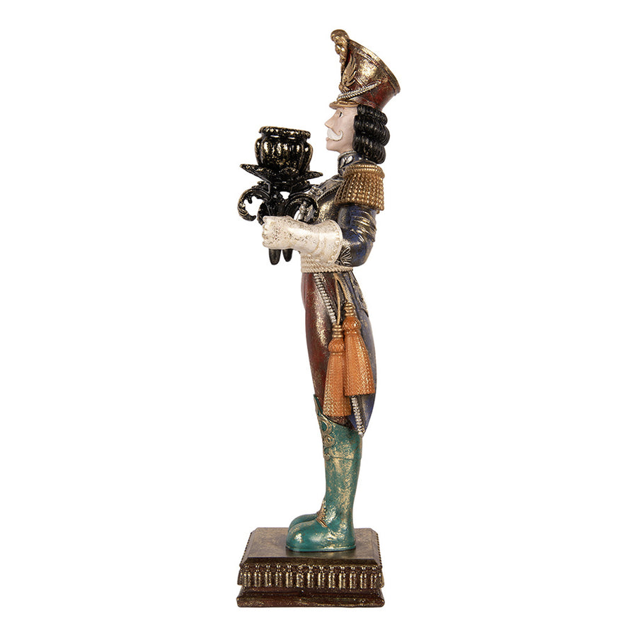 Nutcracker karácsonyi diótörő figura oldalnézetből, aranyszínű vállrojttal, bojtos díszítéssel, zöld csizmával és mintás talapzattal.