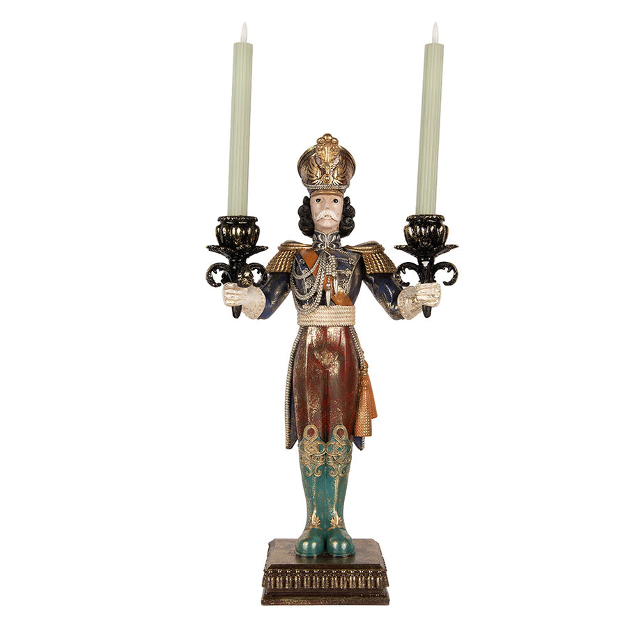 Nutcracker karácsonyi diótörő figura két világoszöld szálgyertyával bemutatva, fekete-arany gyertyatartókkal és patinás díszítéssel.