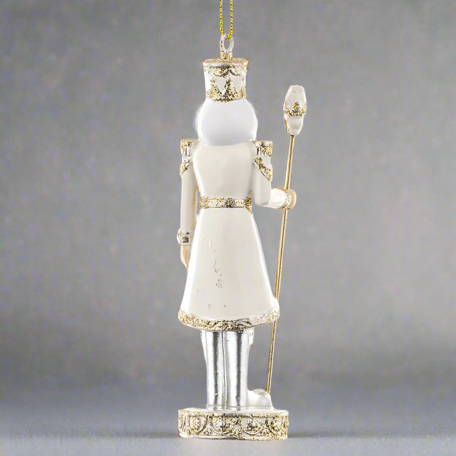 Krém és aranyszínű, diótörő figurás karácsonyfadísz.