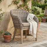 Rattan karosszék teraszon bézs párnával és természetes hangulattal