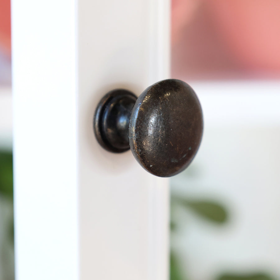 Antikolt hatású fém gombfogantyú közelről az Old French fehér faliszekrényen.