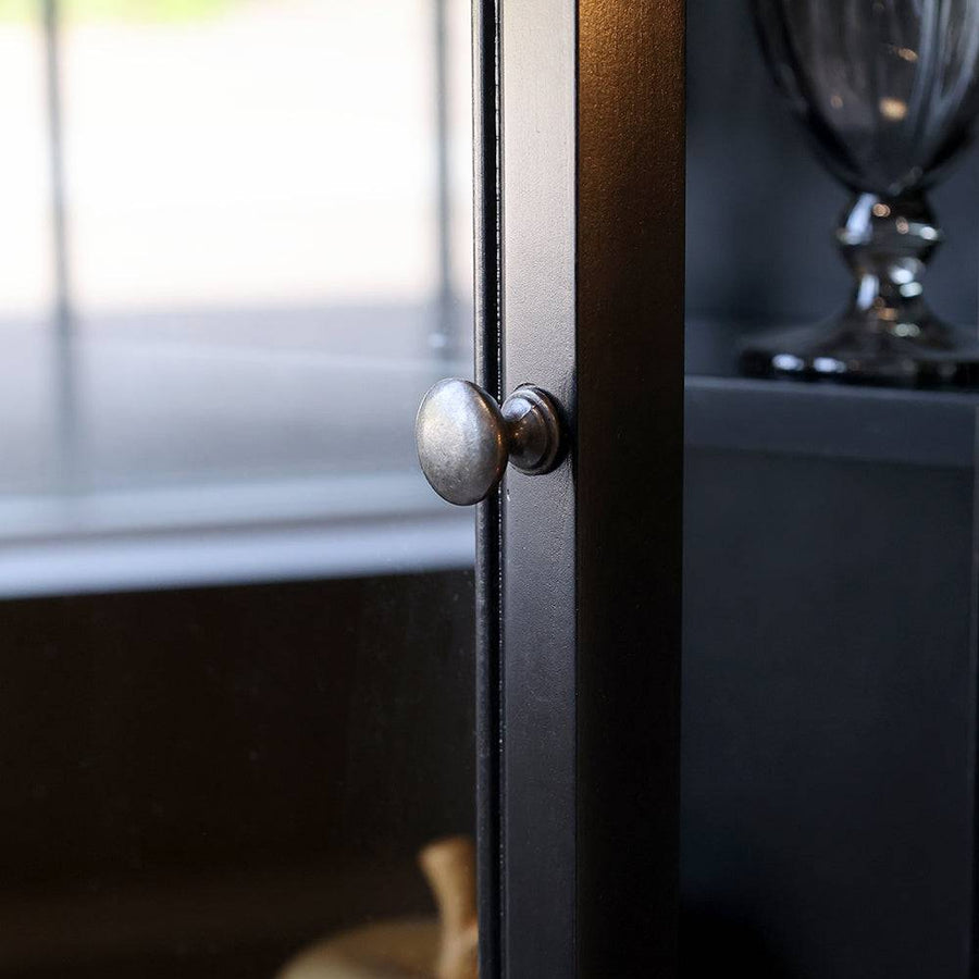 Kerek fém fogantyú a vitrines szekrény üvegajtaján, elegáns antikolt kivitelben.