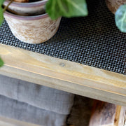 Masszív fémhálós polc fa keretbe foglalva, növényekkel és textíliával.