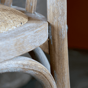 Közeli kép a fonott ülőfelület és fa ülőkeret találkozásáról, finom részletekkel.