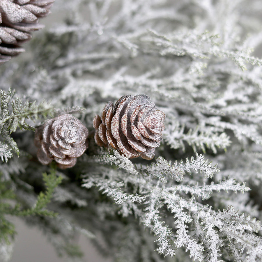 Hóval borított mű fenyő koszorú közeli részlete tobozokkal