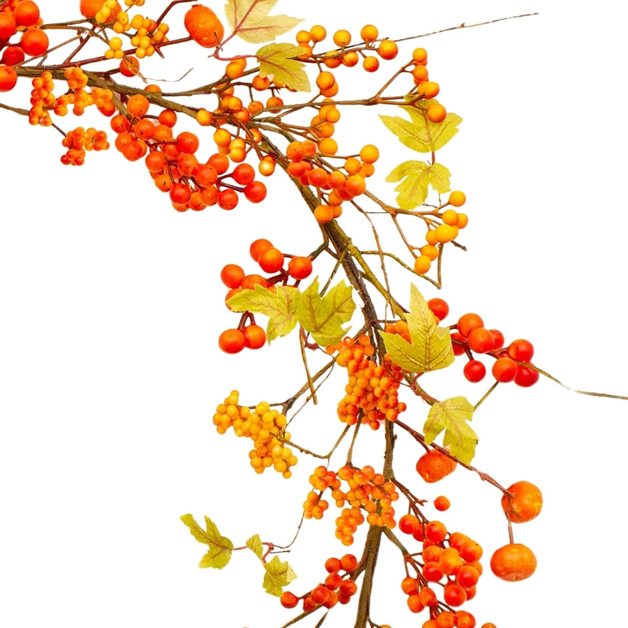 Közelkép őszi mű girlandról, piros bogyókkal és sárguló levelekkel.