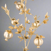 Részletgazdag arany gránátalma ág közeli fotója, dekor levelekkel.