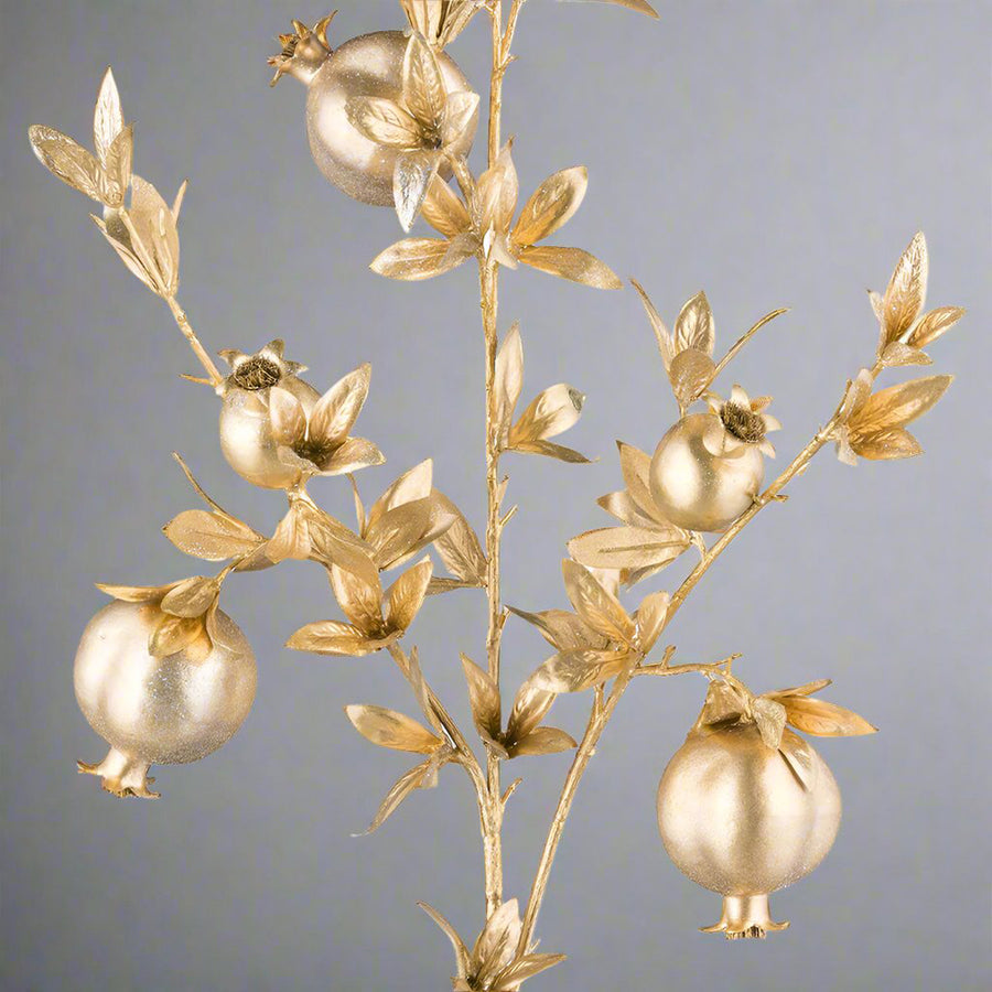 Részletgazdag arany gránátalma ág közeli fotója, dekor levelekkel.