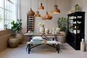 Old French rattan pendant lamp Ø40 cm above a rustic dining table in a bright dining room, natural woven rattan with mango wood top.