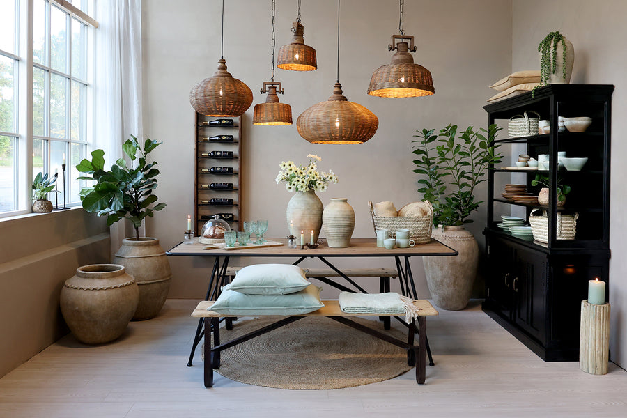 Old French rattan pendant lamp Ø40 cm above a rustic dining table in a bright dining room, natural woven rattan with mango wood top.