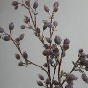 Valósághű mű csipkebogyó ág közeli képe, szürkés-lila színárnyalatú bogyókkal.