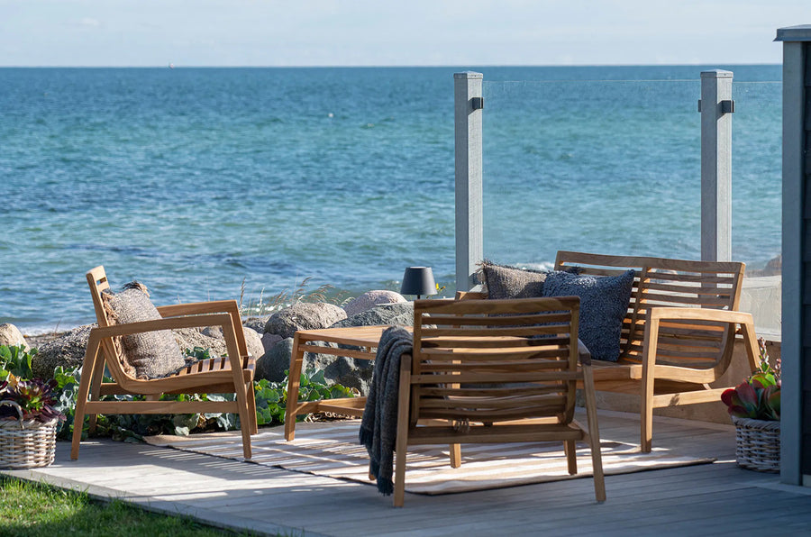 A kerti ülőgarnitúra hátulról fotózva, tengeri panorámával és napfényben úszó természetes környezettel.