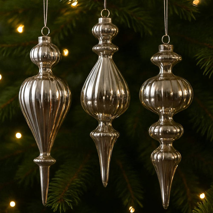 Ezüst üveg jégcsap díszek karácsonyfán, meleg fényekkel megvilágítva.