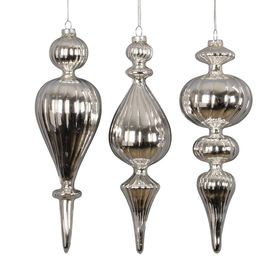 Három darab különböző formájú, ezüst színű üveg jégcsap karácsonyfadísz fehér háttéren.
