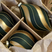 A Shiny üvegdíszek matt olívazöld felületének, fényes arany sávjainak és csillámos vonalainak közeli részlete.