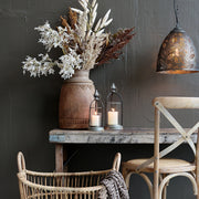 Sorghum mokkaszínű magvas mű ág rusztikus asztalon, lámpás és szék mellett