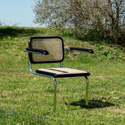 Modern fémvázas, fekete színű, rattan betétes karosszék.